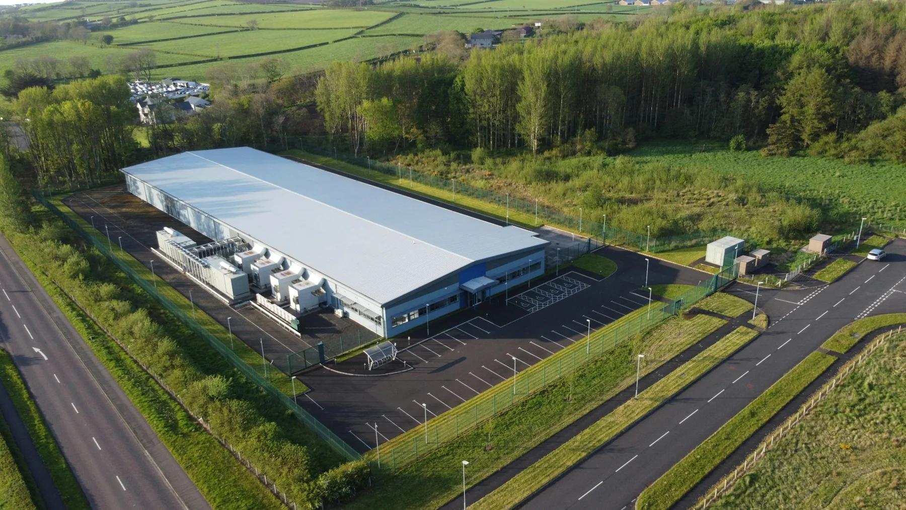 A data center and its utility equipment surrounded by fields and woodland in Coleraine.